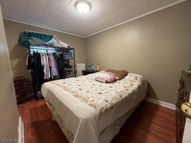 bedroom with dark wood-type flooring, radiator heating unit, and crown molding