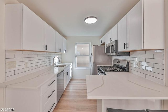 kitchen featuring white cabinetry, kitchen peninsula, a breakfast bar area, appliances with stainless steel finishes, and sink