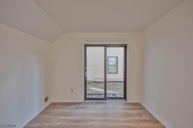 unfurnished room featuring vaulted ceiling, plenty of natural light, and light hardwood / wood-style floors