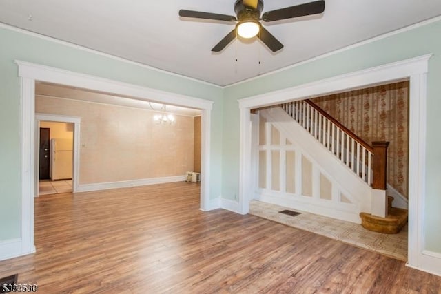 unfurnished room featuring light wood-type flooring, crown molding, and ceiling fan with notable chandelier