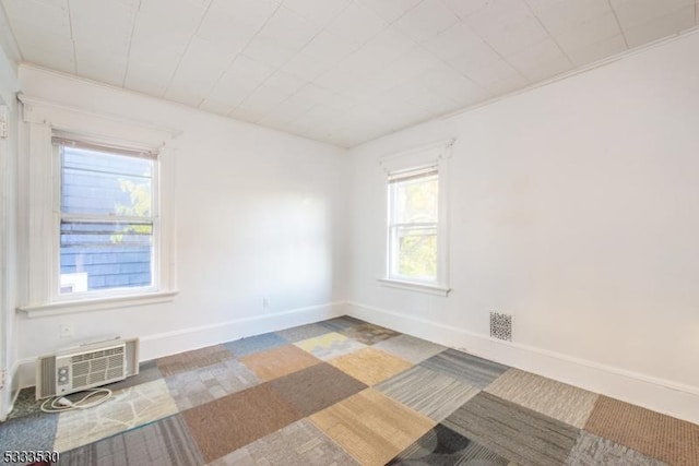 empty room featuring carpet flooring, ornamental molding, and a wall unit AC