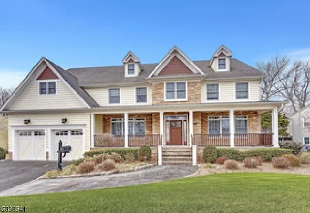 view of front of house featuring a garage, covered porch, and a front lawn