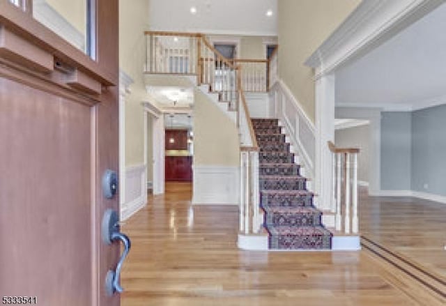 entryway featuring a high ceiling, crown molding, and hardwood / wood-style floors