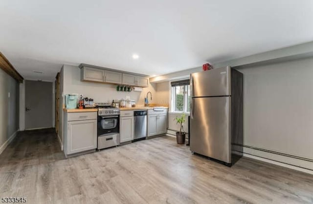 kitchen featuring gray cabinets, appliances with stainless steel finishes, a baseboard radiator, sink, and light wood-type flooring