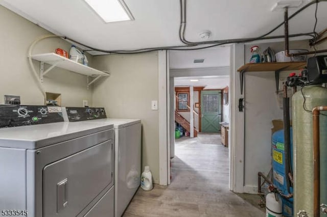 laundry area featuring washer and clothes dryer and light hardwood / wood-style floors