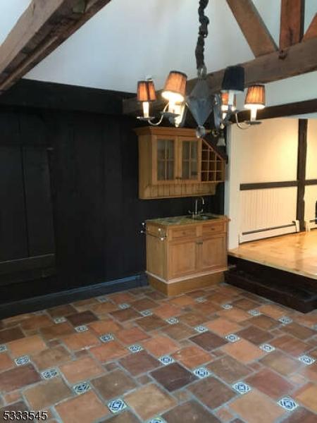 kitchen featuring beamed ceiling, sink, an inviting chandelier, and baseboard heating