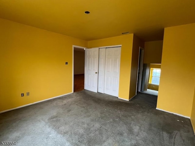 unfurnished bedroom with a closet and dark colored carpet