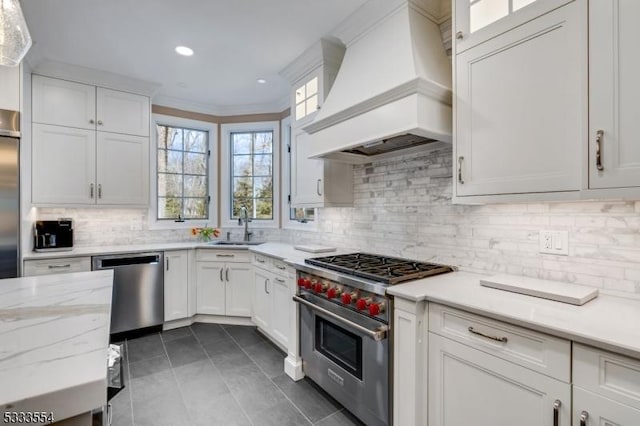 kitchen with stainless steel appliances, custom range hood, white cabinets, decorative backsplash, and crown molding