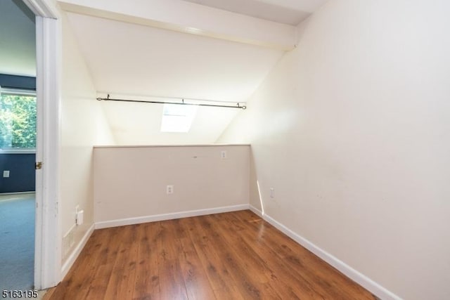 unfurnished room with hardwood / wood-style flooring and lofted ceiling with skylight