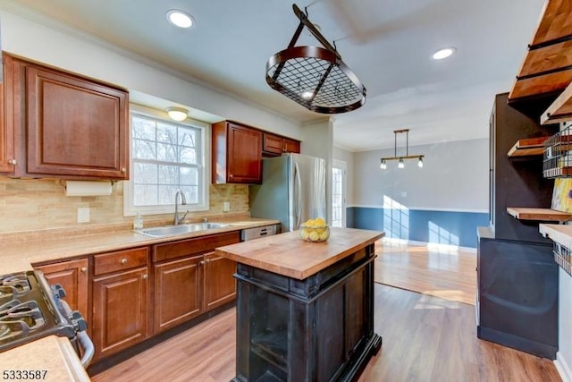 kitchen with pendant lighting, sink, a center island, stainless steel appliances, and light wood-type flooring