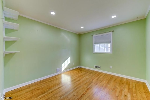 spare room featuring crown molding and light hardwood / wood-style floors