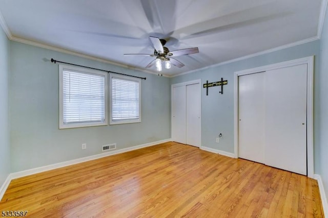 unfurnished bedroom with multiple closets, crown molding, and light hardwood / wood-style flooring