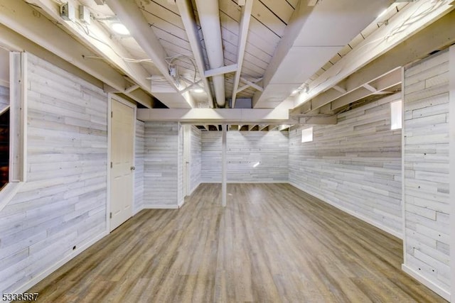 basement featuring wood-type flooring and wooden walls