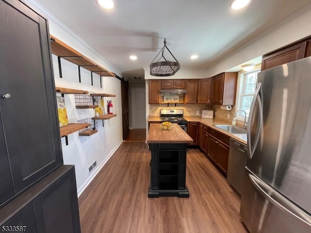 kitchen featuring butcher block counters, sink, wood-type flooring, a kitchen island, and stainless steel appliances