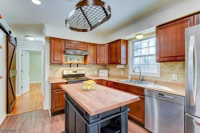 kitchen with butcher block countertops, sink, stainless steel appliances, a center island, and a barn door