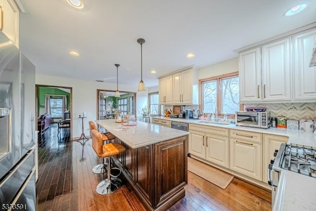 kitchen with a kitchen island, backsplash, a kitchen bar, and decorative light fixtures