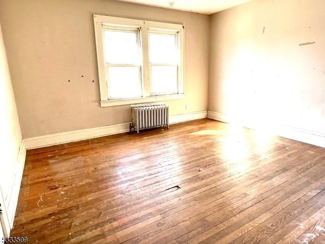 spare room with wood-type flooring and radiator heating unit