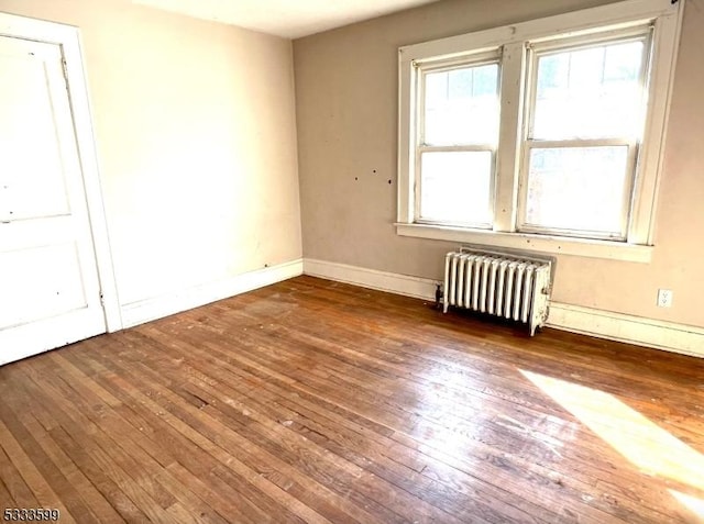 empty room with dark hardwood / wood-style floors and radiator heating unit