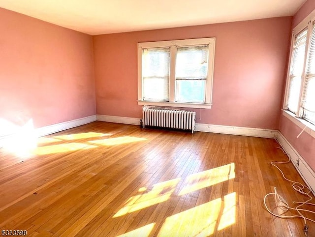 spare room featuring radiator heating unit and light hardwood / wood-style flooring