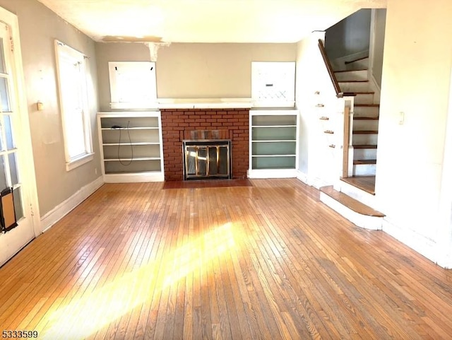 unfurnished living room featuring light wood-type flooring and a brick fireplace