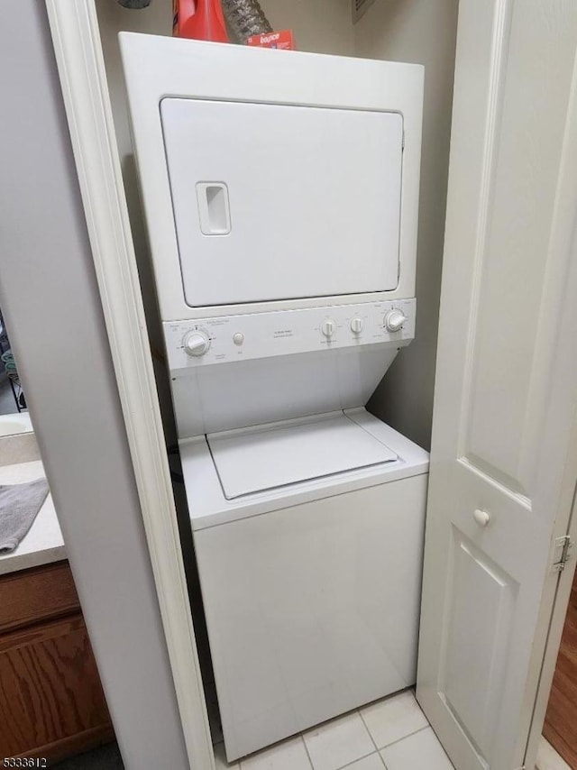 laundry area featuring light tile patterned floors and stacked washer / dryer