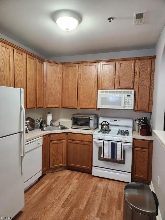 kitchen featuring sink, white appliances, and light hardwood / wood-style flooring