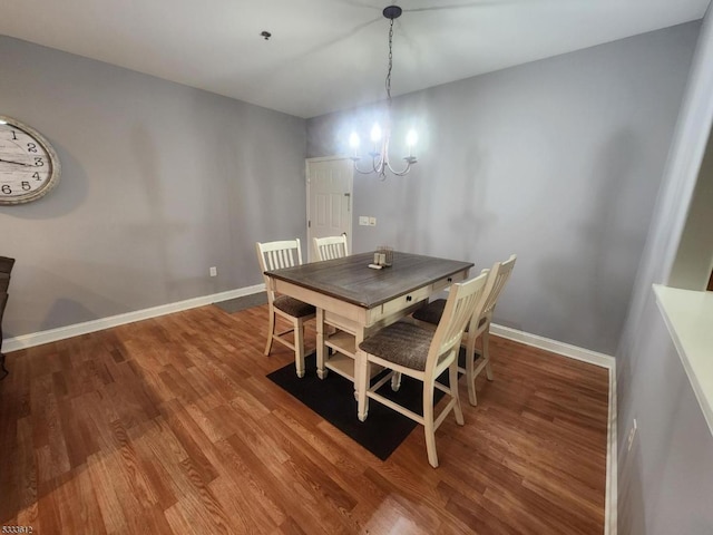 dining area with hardwood / wood-style floors and a notable chandelier