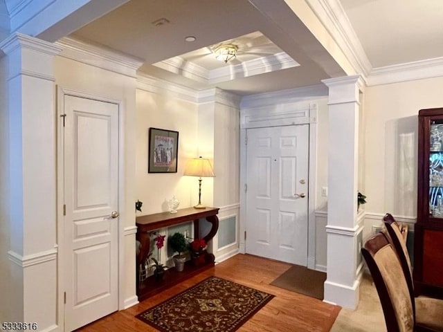 foyer featuring ornate columns, crown molding, and wood-type flooring