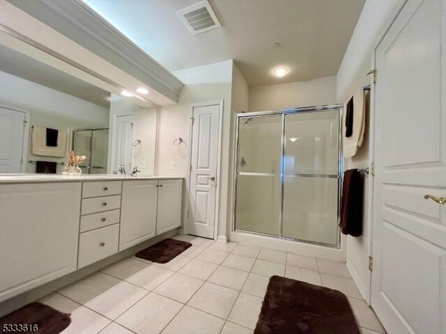 bathroom with a shower with shower door, tile patterned floors, and vanity