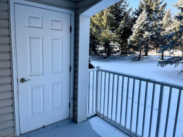 snow covered property entrance featuring a balcony