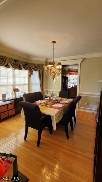 dining area with light hardwood / wood-style flooring, ornamental molding, and a chandelier