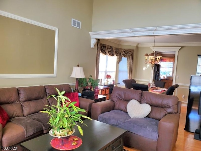 living room with crown molding, an inviting chandelier, and light hardwood / wood-style floors