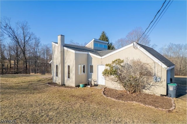 view of property exterior featuring a yard, a garage, roof with shingles, and a chimney