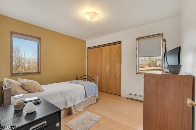 bedroom featuring light wood-style floors, a closet, and baseboard heating