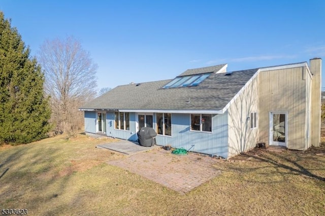 rear view of house featuring a patio area, a lawn, and a shingled roof