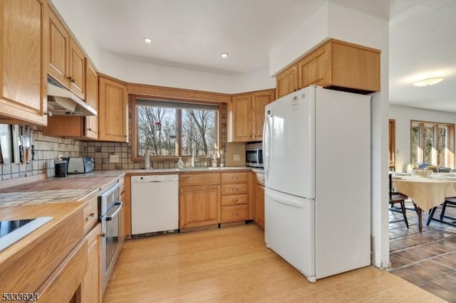 kitchen featuring under cabinet range hood, recessed lighting, light wood-style floors, appliances with stainless steel finishes, and decorative backsplash