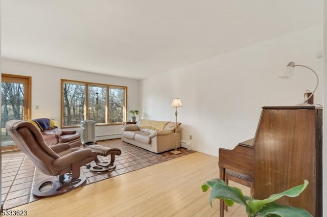 living room featuring a baseboard heating unit, plenty of natural light, wood finished floors, and a baseboard radiator