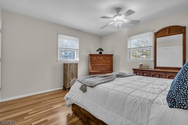 bedroom with light wood-style floors, multiple windows, baseboards, and a ceiling fan