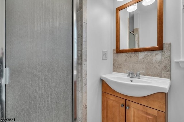 bathroom with a shower with door, decorative backsplash, and vanity