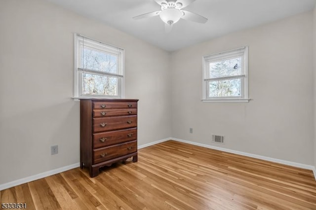 spare room featuring baseboards, a ceiling fan, visible vents, and light wood-style floors