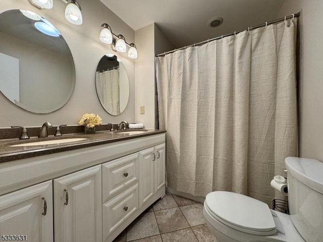 bathroom with double vanity, a sink, toilet, and tile patterned floors