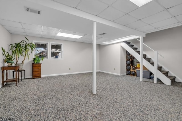 basement with a paneled ceiling, carpet flooring, visible vents, baseboards, and stairway