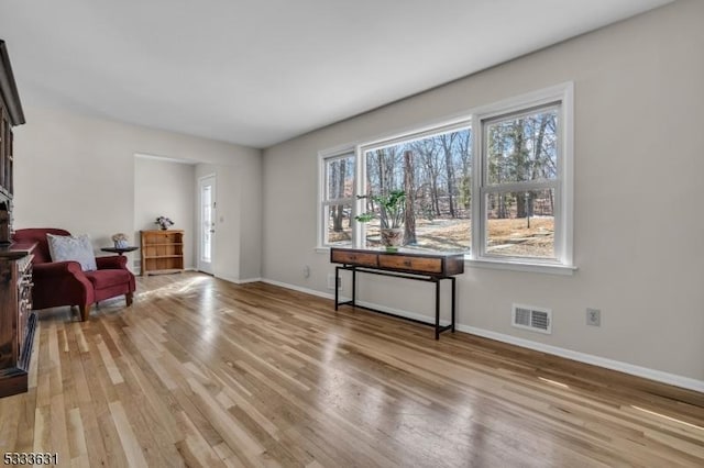 sitting room featuring light wood-type flooring, visible vents, and baseboards