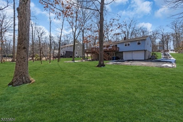 view of yard with a deck, driveway, stairway, and a garage