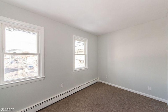 unfurnished room with a baseboard radiator and dark colored carpet