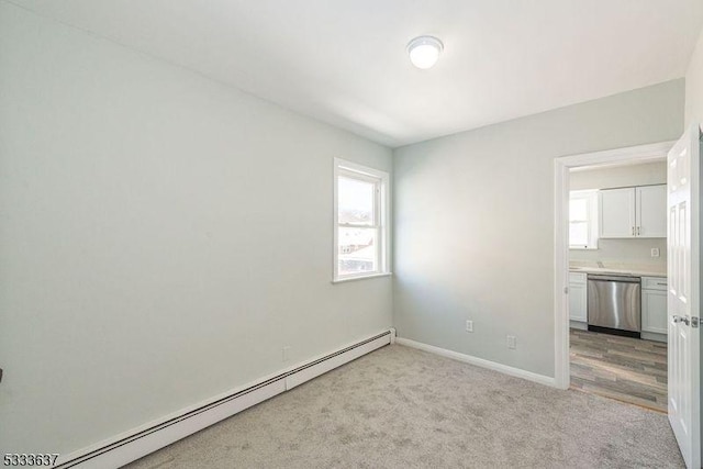 carpeted empty room featuring a baseboard heating unit