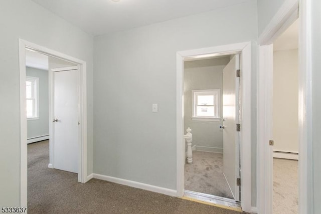 corridor with carpet, a baseboard heating unit, and plenty of natural light