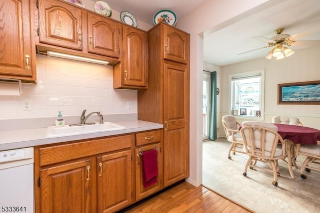 kitchen with dishwasher, sink, decorative backsplash, ceiling fan, and light wood-type flooring