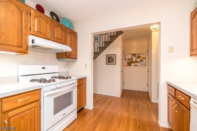 kitchen featuring decorative backsplash, light hardwood / wood-style flooring, and white gas range oven