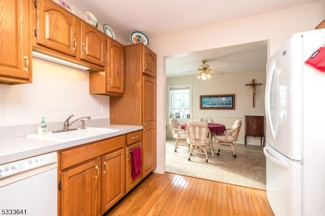 kitchen with sink, tasteful backsplash, light hardwood / wood-style flooring, ceiling fan, and white appliances